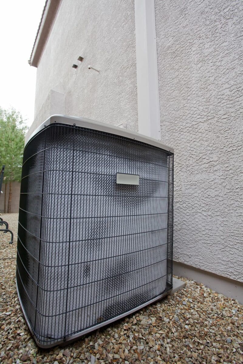 Air conditioning unit in the side yard of a home alongside wall